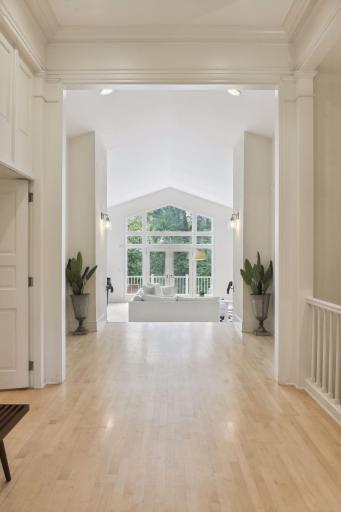 The grand foyer welcomes you in with gleaming hardwood floors, columns, artistic pediments above the doorways, and high ceilings with decorative trim.
