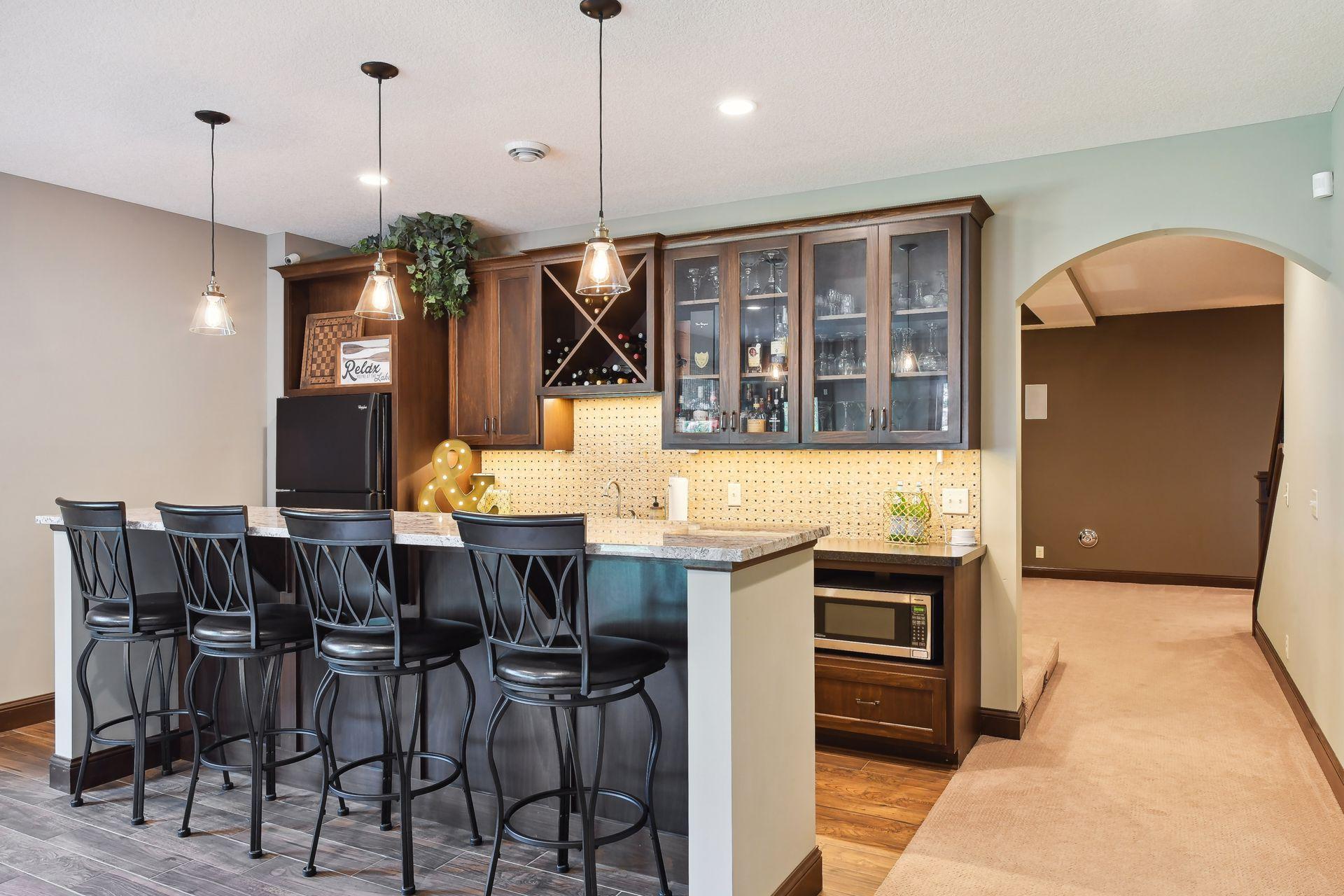 Time for a cocktail to relax after a long day. Nice wet bar with custom cabinetry, tile backsplash, refrigerator, microwave and more.