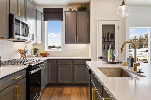 Designer selected cabinet colors, hardware, countertops and backsplash complement each kitchen. This picture is of the model home.