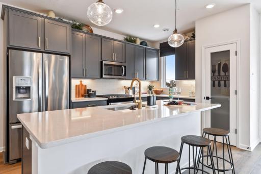 Designer selected cabinet colors, hardware, countertops and backsplash complement each kitchen. This picture is of the model home.