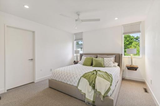 Primary bedroom with built in nightstands, customized walk-in closet, recessed lighting and sleek ceiling fan.