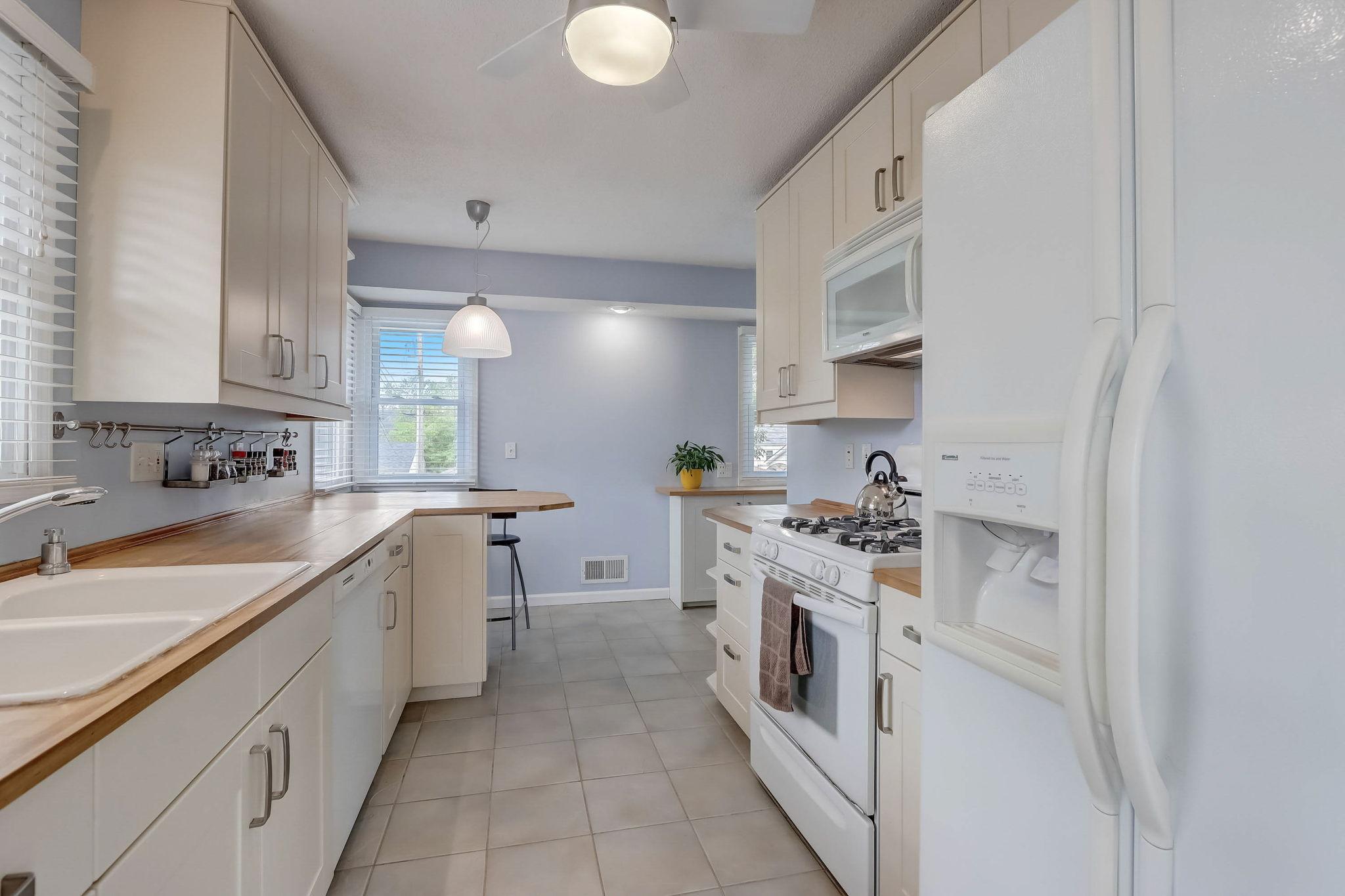 Fantastic kitchen provides extensive storage with updated cabinetry, butcher block countertops, tile floor, and breakfast bar seating.