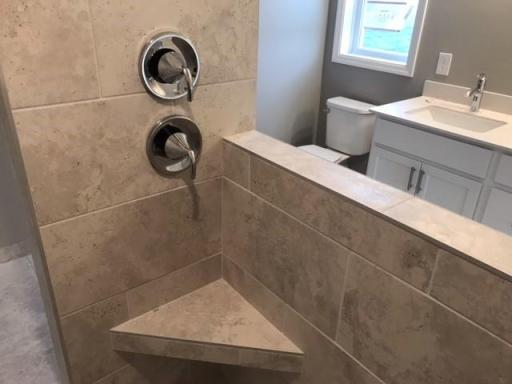 Walk-in shower has seat and front glass. Finishes will vary