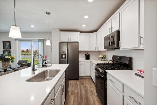Equipped with stainless appliances, quartz countertops, a kitchen island and plank-style flooring throughout, this kitchen adds distinction & character to the home. *Photos are of another model, colors and finishes may vary.