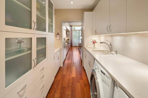 Gorgeous, clean white cabinets flank both sides of this laundry room/hallway. Ample storage area with convenient racks/shelving. Also features a pull out pantry for spices or small items.