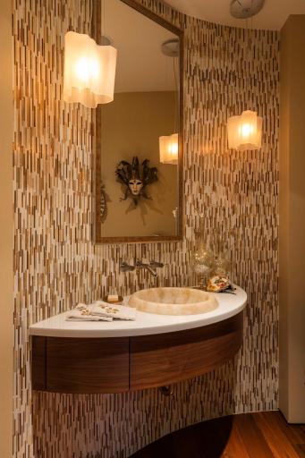 Powder room directly off kitchen with intricate tile work, onyx sink and quartz countertop.