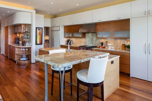 Thoughtful wet bar built into the curved wall with Viking wine cooler and glass shelving, accented by mosaic tile, Brazilian walnut and frosted glass cabinetry.