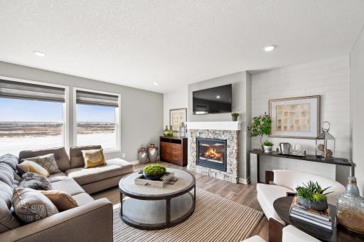 Soaring windows provide an abundance of natural light to flow throughout the main level, including this nicely sized family room, featuring a natural gas fireplace. Model Floorplan. Actual home finishes will vary.