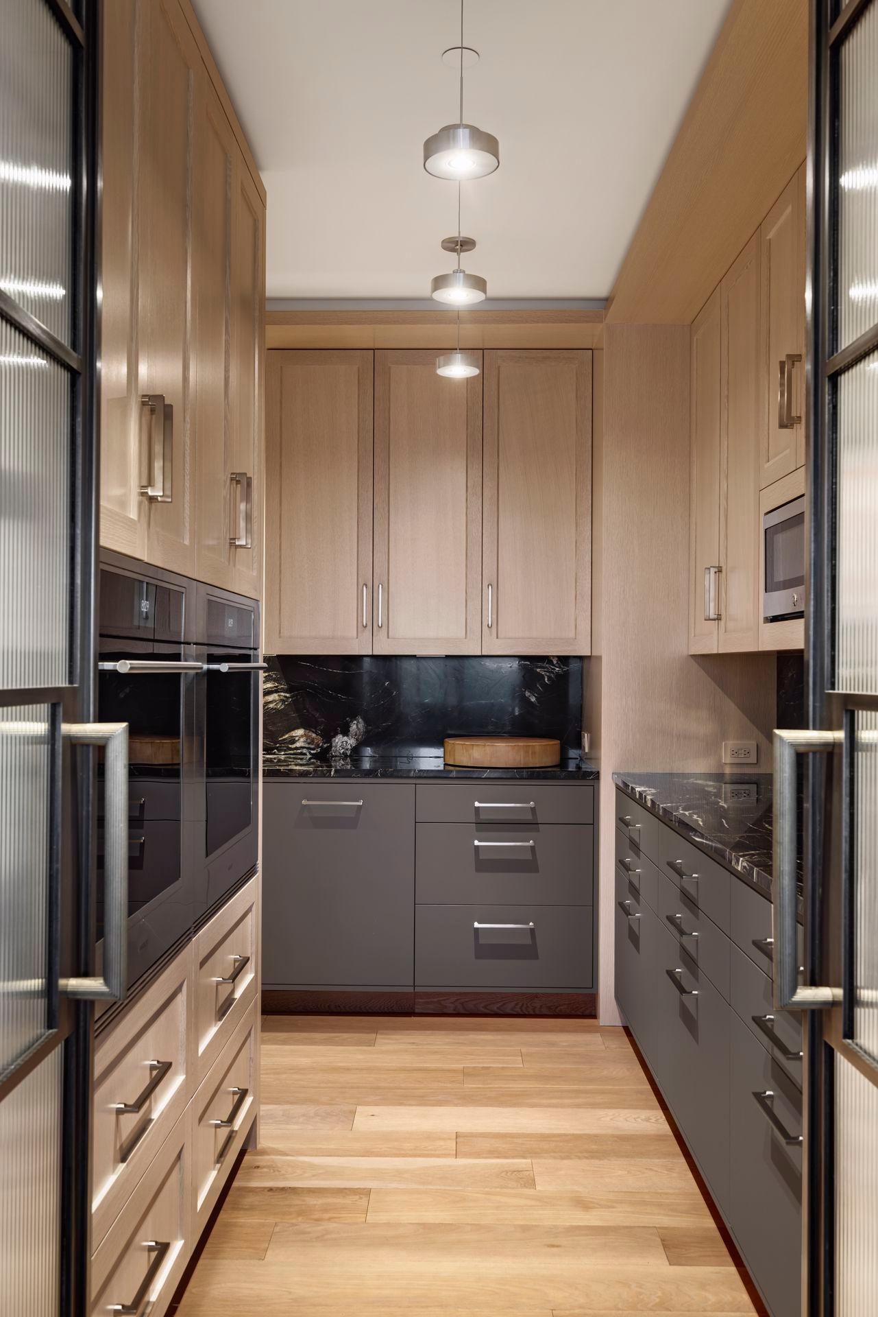 There are two Wolf ovens on the left, a microwave on the right, and generous oak cabinetry and granite countertops and backsplashes throughout.