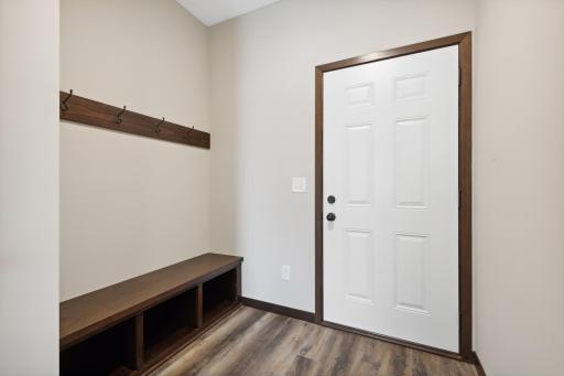 MODEL PHOTO - Well designed mudroom off garage with coat hooks, built in bench and coat closet!