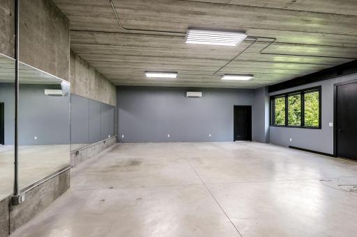 Tuck under 3 stall garage, previously used as a weight room equipped with full wall of mirrors. Wired for speakers and has dedicated power source for necessary. Ductless mini-split AC/Heat in closed-off tuck under. 4th stall threw the door for toys.
