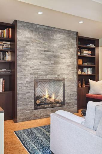 Gorgeous slate stacked gas fireplace is flanked by custom built-in cabinets.