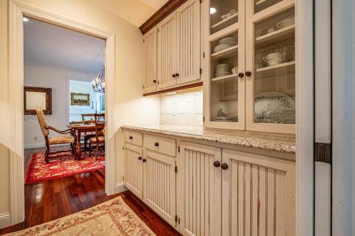 Butler's pantry with walk-through access to the formal dining room features a sink with hot and cold water and under cabinet lighting.