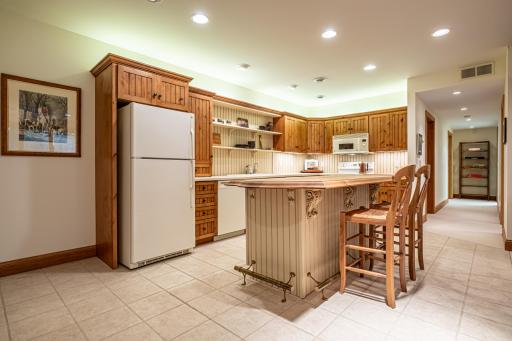 Lower level kitchen features pine cabinets, center island, tile flooring, under cabinet lighting, and recessed lighting.