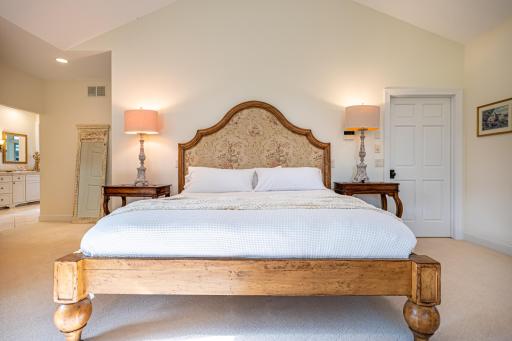 Primary bedroom features a large picture window, vaulted ceiling, recessed lighting, double walk-in closets, and an ensuite bathroom.