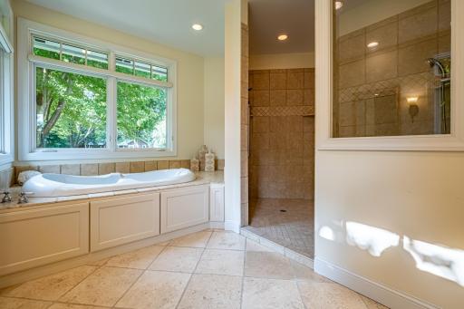 Primary bathroom features a large vanity with double sinks and storage, a jacuzzi tub, walk-in tile shower with double shower heads, recessed lighting, and a private toilet area.