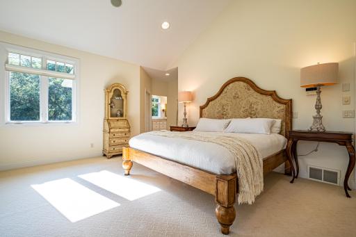 Primary bedroom features a large picture window, vaulted ceiling, recessed lighting, double walk-in closets, and an ensuite bathroom.