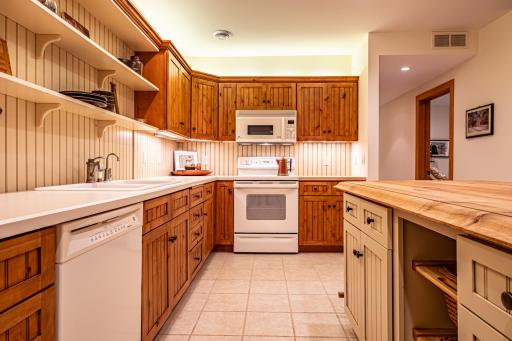 Lower level kitchen features pine cabinets, center island, tile flooring, under cabinet lighting, and recessed lighting.