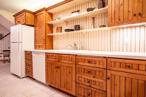 Lower level kitchen features pine cabinets, center island, tile flooring, under cabinet lighting, and recessed lighting.
