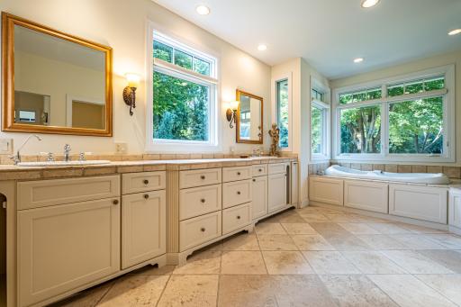 Primary bathroom features a large vanity with double sinks and storage, a jacuzzi tub, walk-in tile shower with double shower heads, recessed lighting, and a private toilet area.