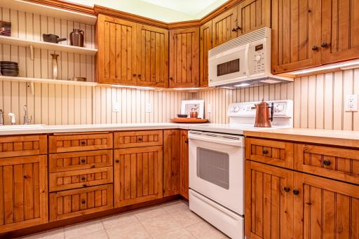 Lower level kitchen features pine cabinets, center island, tile flooring, under cabinet lighting, and recessed lighting.