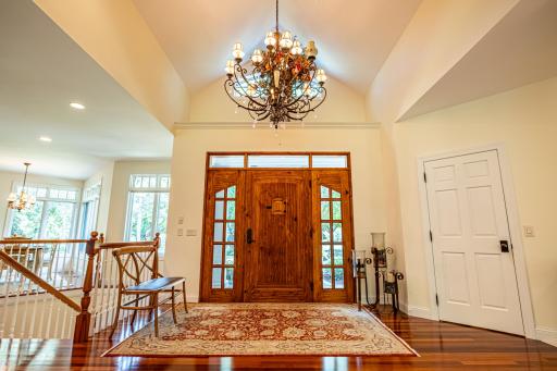 Grand front foyer with custom wood door. Large chandelier over the front entrance. Brazilian walnut floors throughout the main level. Curved paver driveway lead up to the entrance.