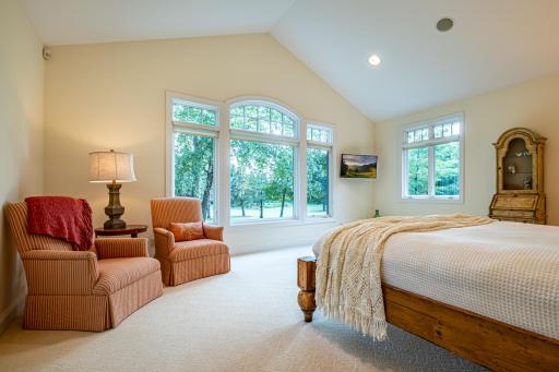 Primary bedroom features a large picture window, vaulted ceiling, recessed lighting, double walk-in closets, and an ensuite bathroom.
