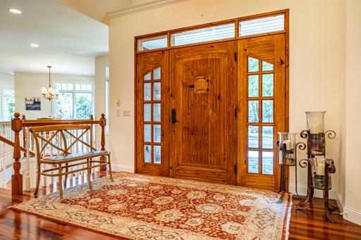 Grand front foyer with custom wood door. Large chandelier over the front entrance. Brazilian walnut floors throughout the main level. Curved paver driveway lead up to the entrance.