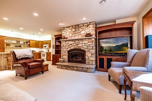 Lower level family room features a stone gas burning fireplace, recessed lighting, a study, and a full kitchen.