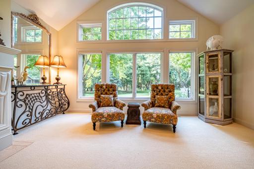 Main floor formal living room features a gas burning fireplace, vaulted ceilings, large windows, and pillars.