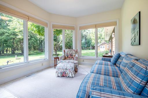 Sunroom on the main floor features many windows with beautiful views of the backyard and tile flooring.