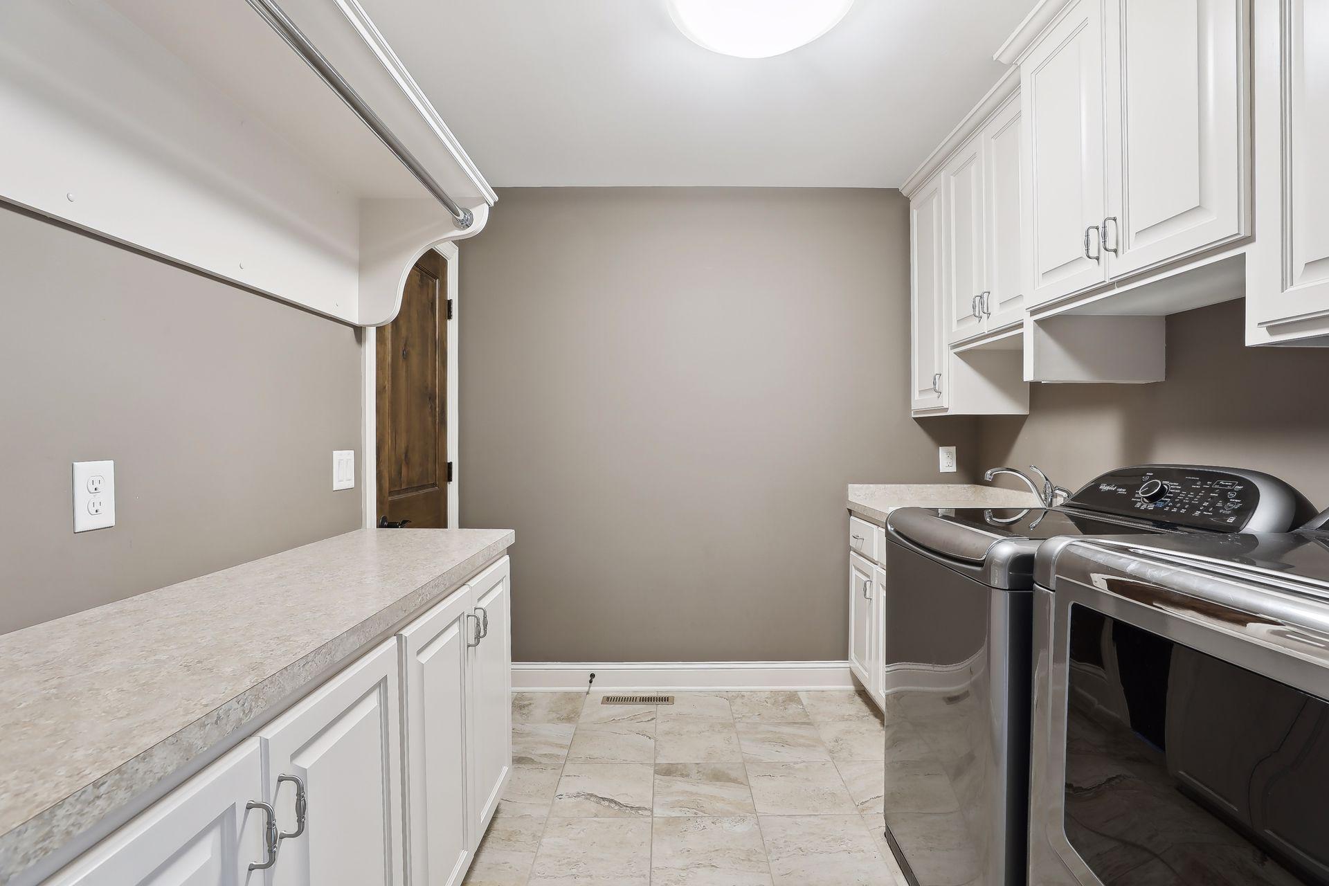 Upper level laundry room has ample storage and hanging rack.