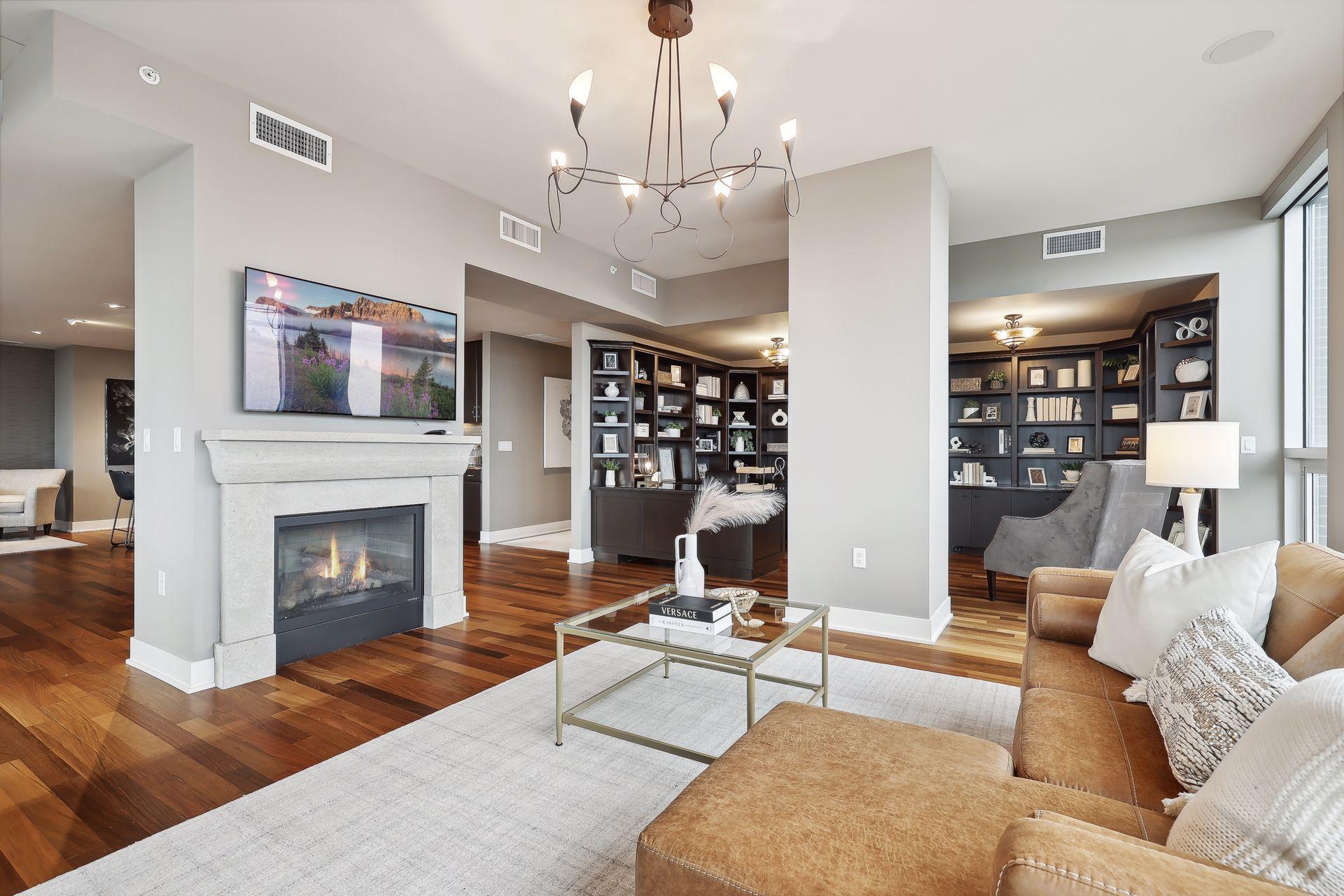 A cozy spot by the fire, and adjacent to the library/office area to grab a good book! Unique lighting fixture is a fun design. A Large screen tv is above the fireplace.