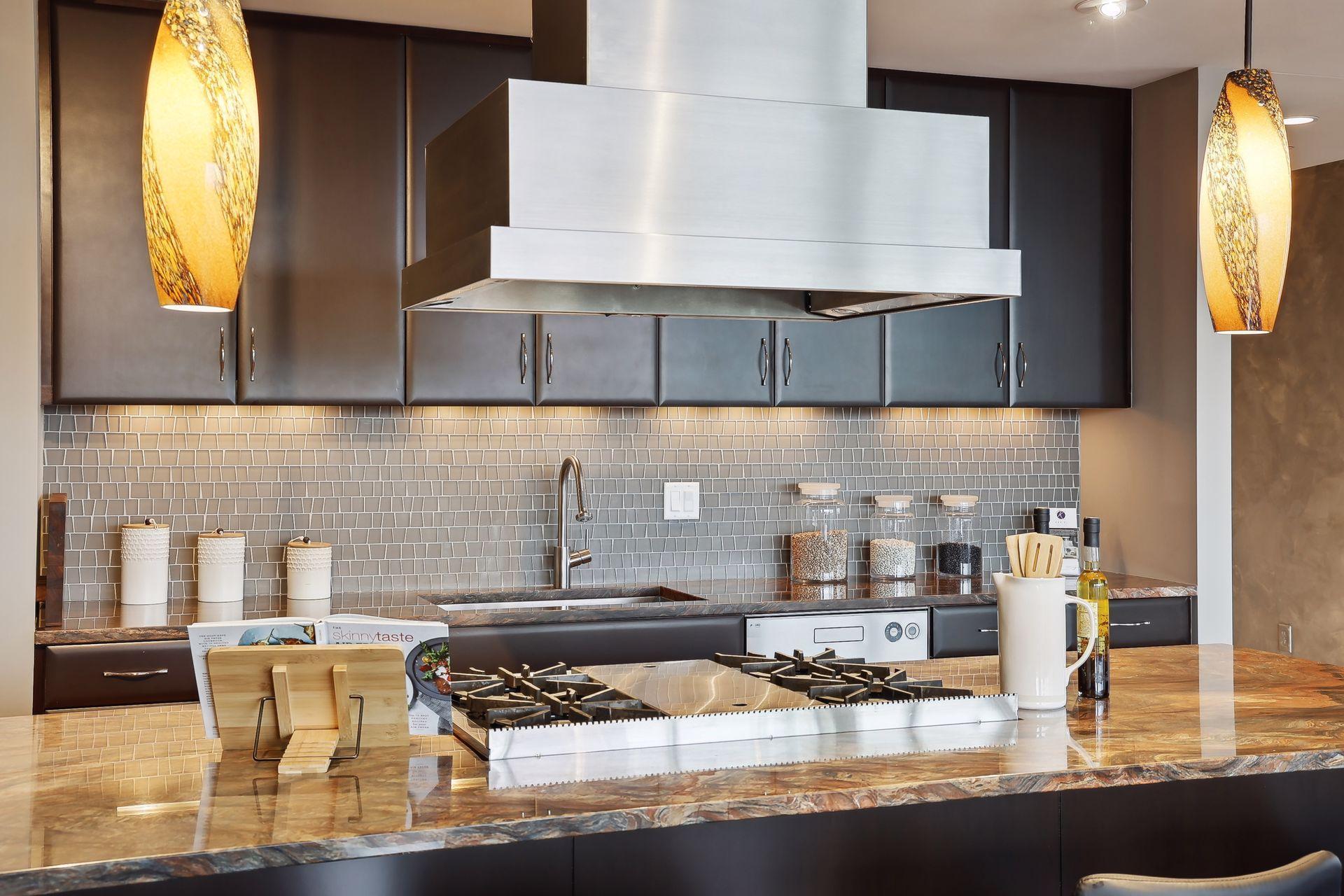 Beautiful marble counter top surrounds the Wolf range top with griddle in the middle. The sea glass back splash is not only stunning but easy to clean. Note the cabinet lighting.