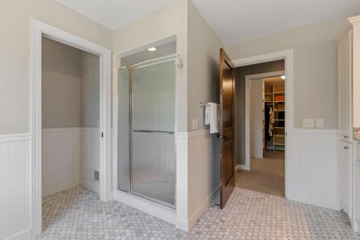 Custom shower features classic subway tiles surround, built-in bench, dual shower heads, marble tile flooring and decorative glass door enclosure