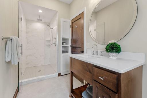 Custom shower features modern tile surround and frameless glass door enclosure w/ porcelain tile flooring
