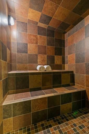 Custom steam/ sauna shower with full tile surround and benches w/ slanted ceiling in the corner so you never get dripped on!