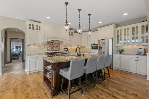 Custom enameled cabinetry features glass and raised panel doors, under cabinet accent lighting, roll-out storage, charming accents including decorative fluted legs and corbels