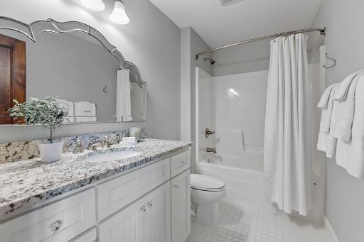 Enameled vanity cabinet w/ beadboard paneled doors, granite countertop and widespread faucet plus mosaic tile flooring