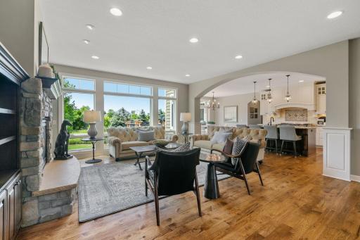 The great room is centered around a gas fireplace with a cultured stone surround and raised hearth, creating a cozy and inviting atmosphere.