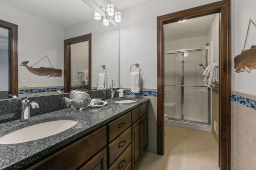 Large alder vanity cabinet w/ granite countertop and dual sinks. Modern tile wainscoting and flooring w/ glass accents
