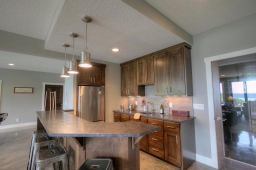 The wet-bar has birch cabinets, Terrazzo granite counters, and a stainless steel refrigerator.