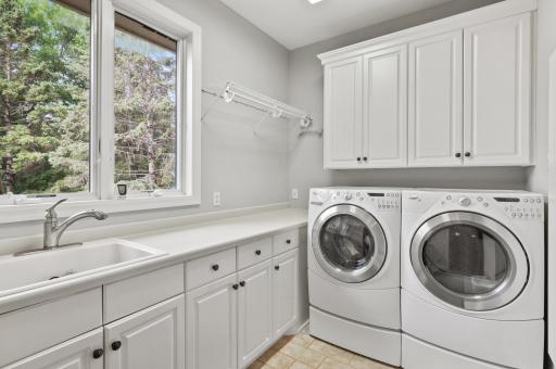 The main level laundry room has ample storage, hanging space, and a sink to handle all your laundry needs.