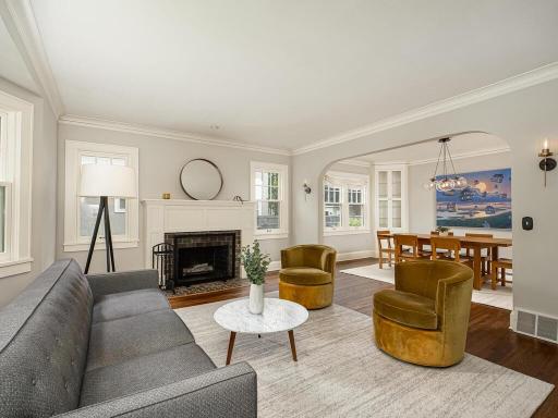 Inviting front entry living room with enameled fireplace, bay window for natural light and archway open to dining.