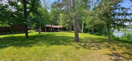 View of the front yard on the riverside looking at the back of one of the garages and guest house. Lots of mature trees.