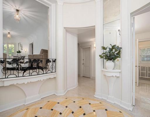 Inviting grand foyer with marble floor, Juliet balcony, elaborate enameled woodwork, main floor guest powder room and separate coat closet.