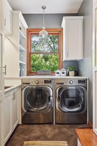 Main level laundry room- pull out hamper, large washing sink, and convenient laundry folding and sorting station
