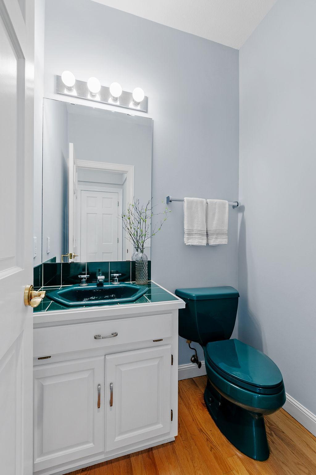 Powder Bath features an enameled vanity cabinet w/ tile countertop and oak hardwood flooring