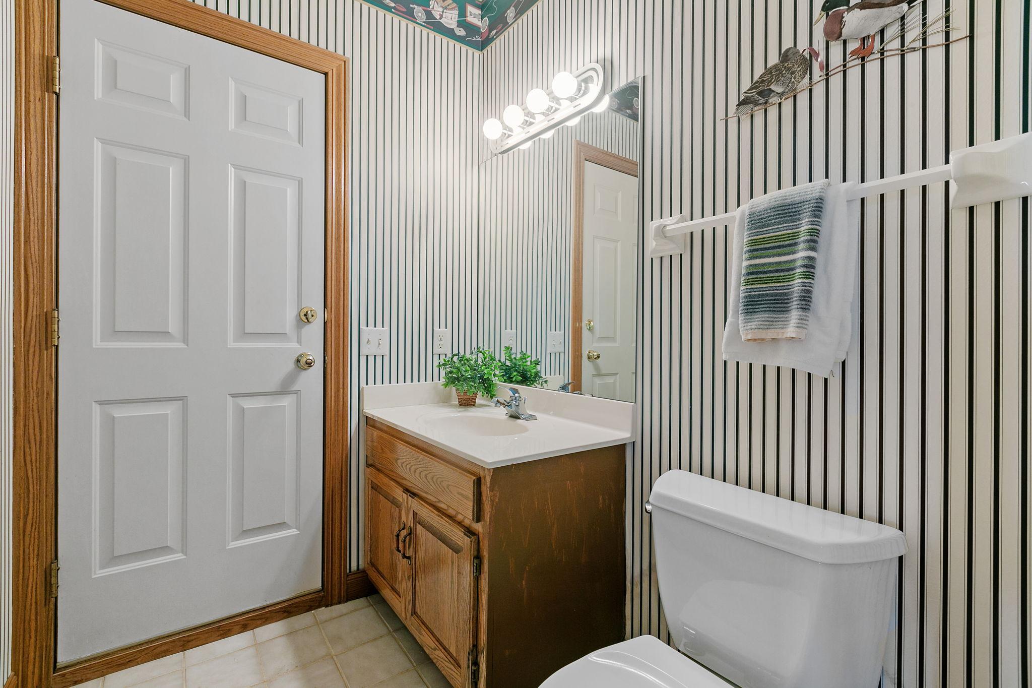 Lower Level 1/2 bath offers an oak vanity cabinet and ceramic tile flooring