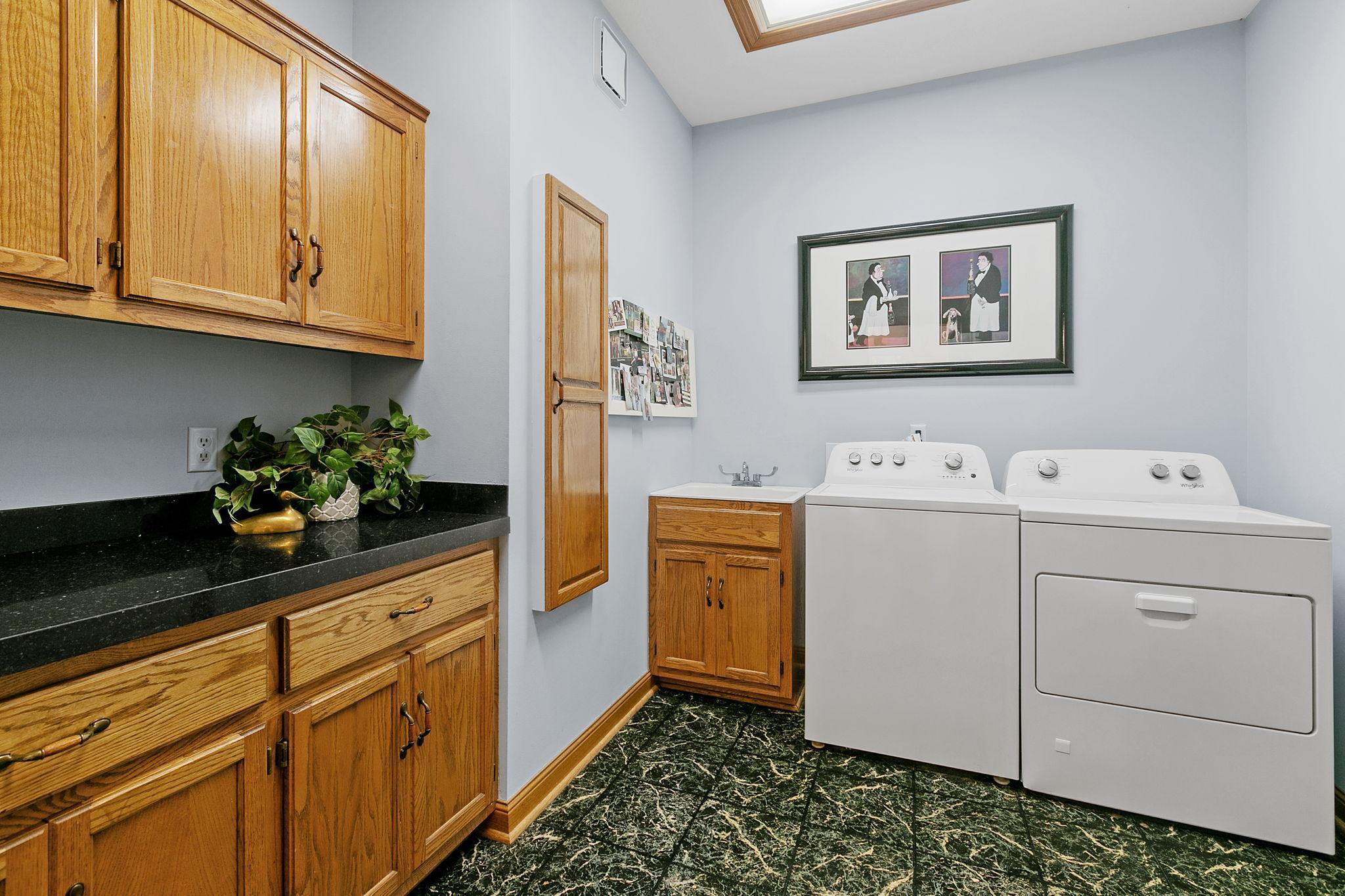 Main floor Laundry Room features oak cabinetry which offers great storage, large granite countertop, drop-in utility sink and ironing board